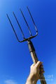 mans-hand-holding-up-pitchfork-against-blue-sky-sami-sarkis.jpg