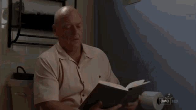 a man is looking at a piece of paper while watching a tv show called breaking bad .